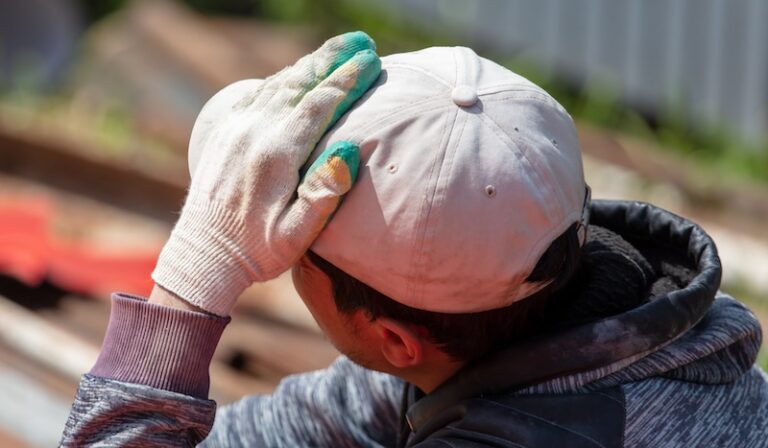 Worker holds his head at a construction site.