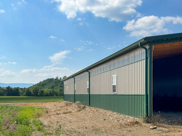 Side view of a barn with an evergreen standing seam roof and clay siding